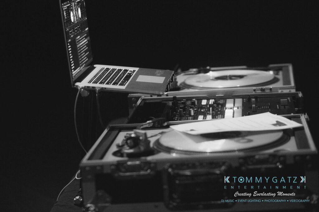 LWYD-Comedy-Tour-Baltimore-060118-FINALS-Low-Res-Watermark-44 - TOMMY GATZ ENTERTAINMENT Black and white image of DJ equipment with turntables and a laptop on a dark surface, featuring Tommy Gatz Entertainment branding.