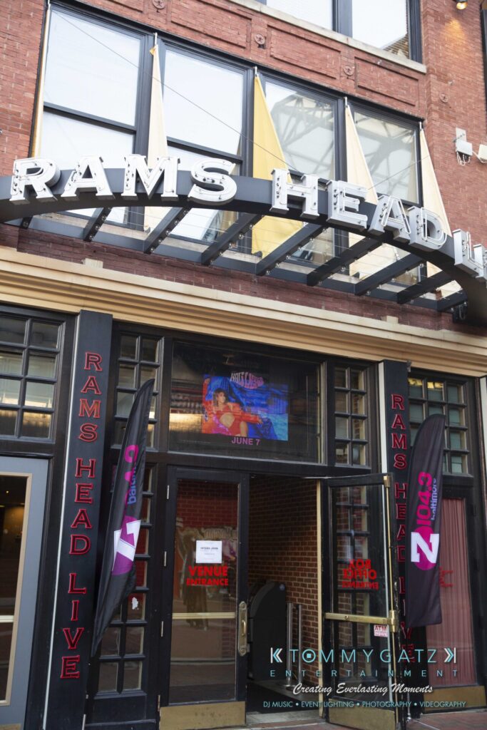 LWYD-Comedy-Tour-Baltimore-060118-FINALS-Low-Res-Watermark-56 - TOMMY GATZ ENTERTAINMENT Entrance of Rams Head Live, featuring large signage and promotional flags. A television screen displays an event schedule inside the venue.