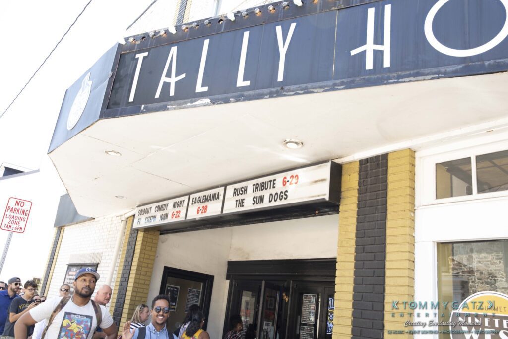062219-Leesburg-TALLY-HO-Low-Res-WM-8-1 - TOMMY GATZ ENTERTAINMENT People entering a venue with a marquee sign that reads "Sonny Comedy Night, Clebama, Rush Tribute, The Sun Dogs." The building has a partially visible "Tally Ho" sign.