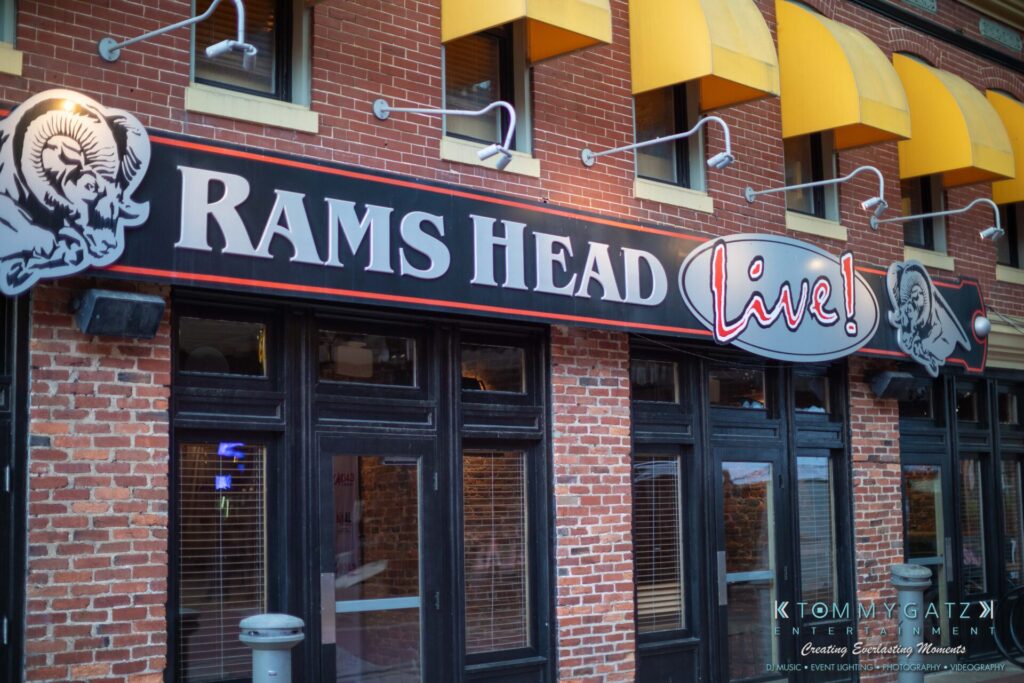 081019-Baltimore-RAMS-HEAD-Low-Res-WM-13 - TOMMY GATZ ENTERTAINMENT Rams Head Live" venue exterior with brick facade, yellow awnings, and a marquee sign featuring ram graphics.