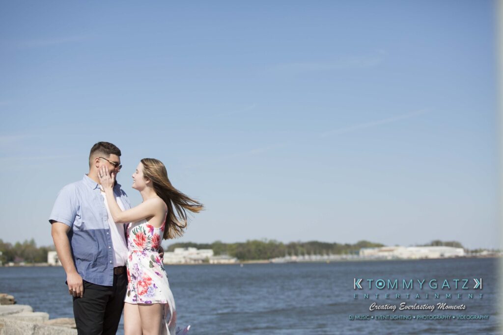 Kari-Jose-43018-FINALS-Low-Res-WM-21 - TOMMY GATZ ENTERTAINMENT A couple stands by a waterfront. The woman touches the man's face while they both smile. It's a sunny day with a clear blue sky.