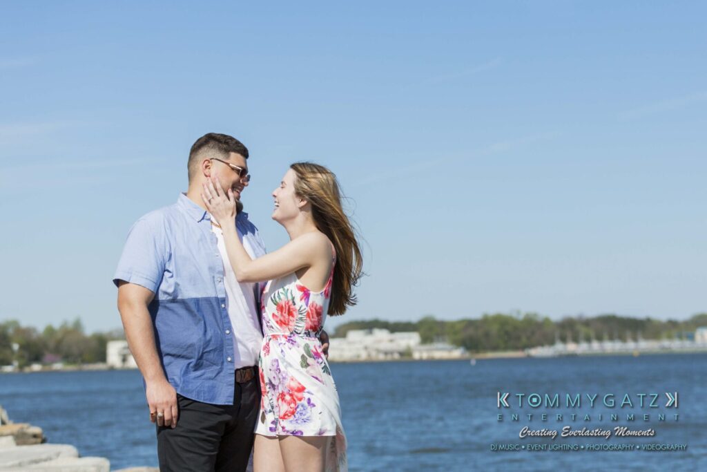 Kari-Jose-43018-FINALS-Low-Res-WM-22 - TOMMY GATZ ENTERTAINMENT A couple stands by the waterfront, with the woman touching the man's face. The sky and water create a serene backdrop.