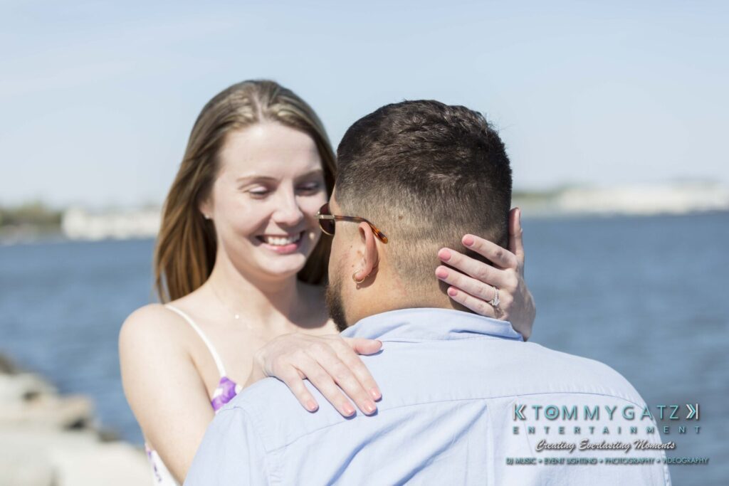 Kari-Jose-43018-FINALS-Low-Res-WM-28 - TOMMY GATZ ENTERTAINMENT A couple stands close on a waterfront, with the woman smiling and resting her hands on the man's shoulders.