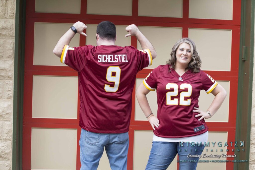 Lisa-Robert-Engagement-042218-Low-Res-Watermark-52 - TOMMY GATZ ENTERTAINMENT Two people wearing matching maroon sports jerseys with numbers 9 and 22. The person on the left is flexing their arms, and the person on the right is smiling with hands on hips.