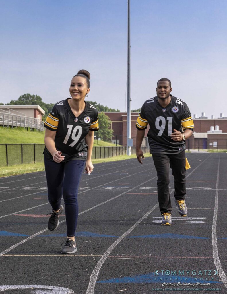 051919-Viona-Kevin-FINALS-Low-RES-WM-1 - TOMMY GATZ ENTERTAINMENT Two people wearing matching sports jerseys run on a track outdoors.