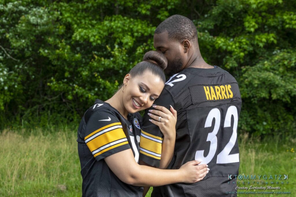 051919-Viona-Kevin-FINALS-Low-RES-WM-12 - TOMMY GATZ ENTERTAINMENT A man and woman wearing matching football jerseys embrace in a grassy outdoor setting.