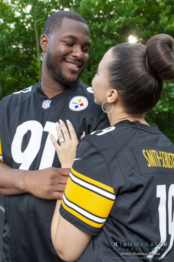 051919-Viona-Kevin-FINALS-Low-RES-WM-15 - TOMMY GATZ ENTERTAINMENT A couple dressed in matching football jerseys smiles at each other while standing outdoors.