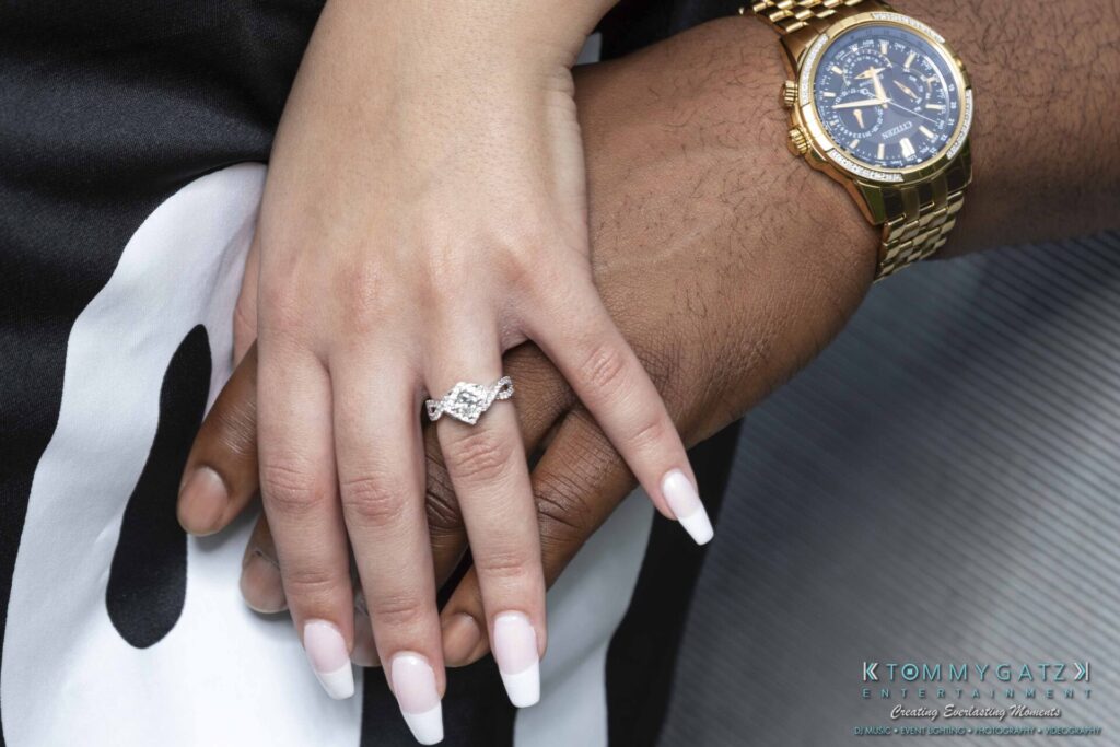 051919-Viona-Kevin-FINALS-Low-RES-WM-25 - TOMMY GATZ ENTERTAINMENT Close-up of two hands; one wearing a gold watch, and the other with a diamond ring, resting on black and white fabric.