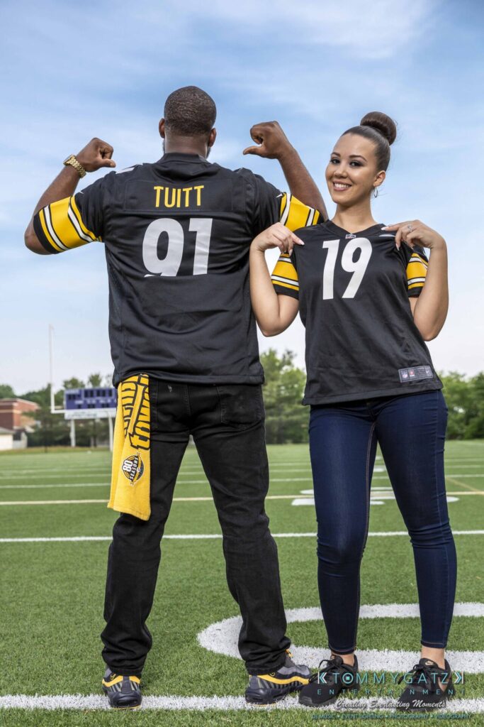 051919-Viona-Kevin-FINALS-Low-RES-WM-28 - TOMMY GATZ ENTERTAINMENT Two people on a football field wearing black and gold jerseys. The left person shows the back with "Tuitt" and "91," while the right person shows the front with "19.