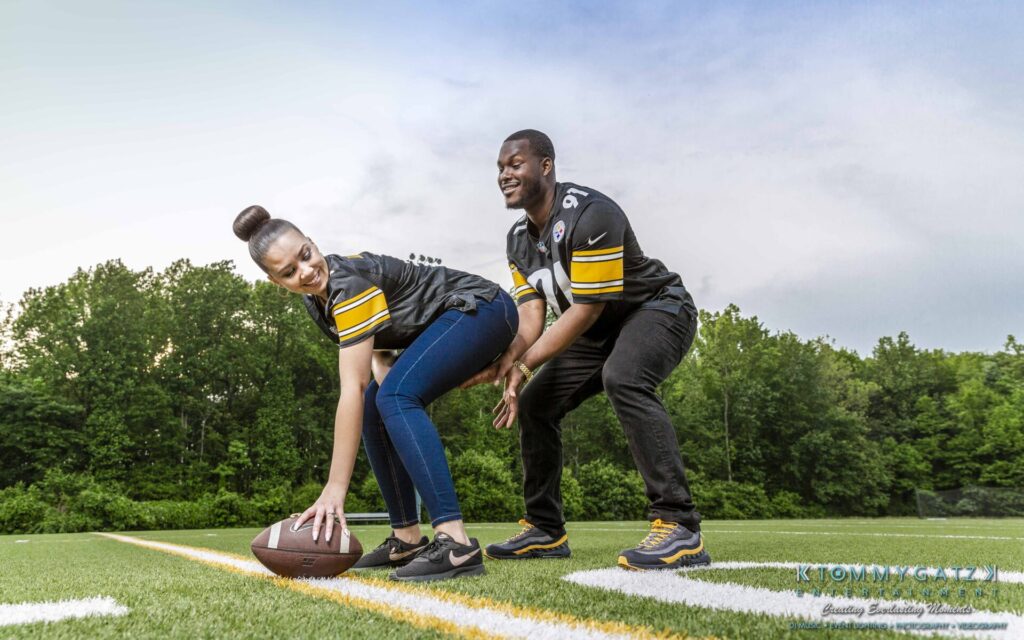 051919-Viona-Kevin-FINALS-Low-RES-WM-40 - TOMMY GATZ ENTERTAINMENT A woman prepares to hike a football while a man stands behind her on a football field. Both are wearing black and yellow sports jerseys.