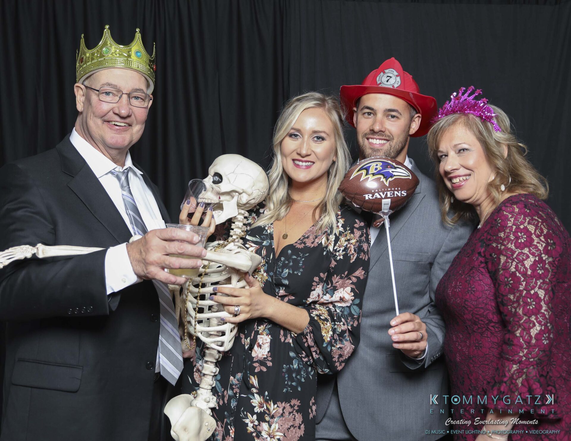 Megan-Matt-102718-Blow-WM-12 - TOMMY GATZ ENTERTAINMENT Four people in festive outfits posing with a skeleton, a crown, and a Baltimore Ravens balloon.