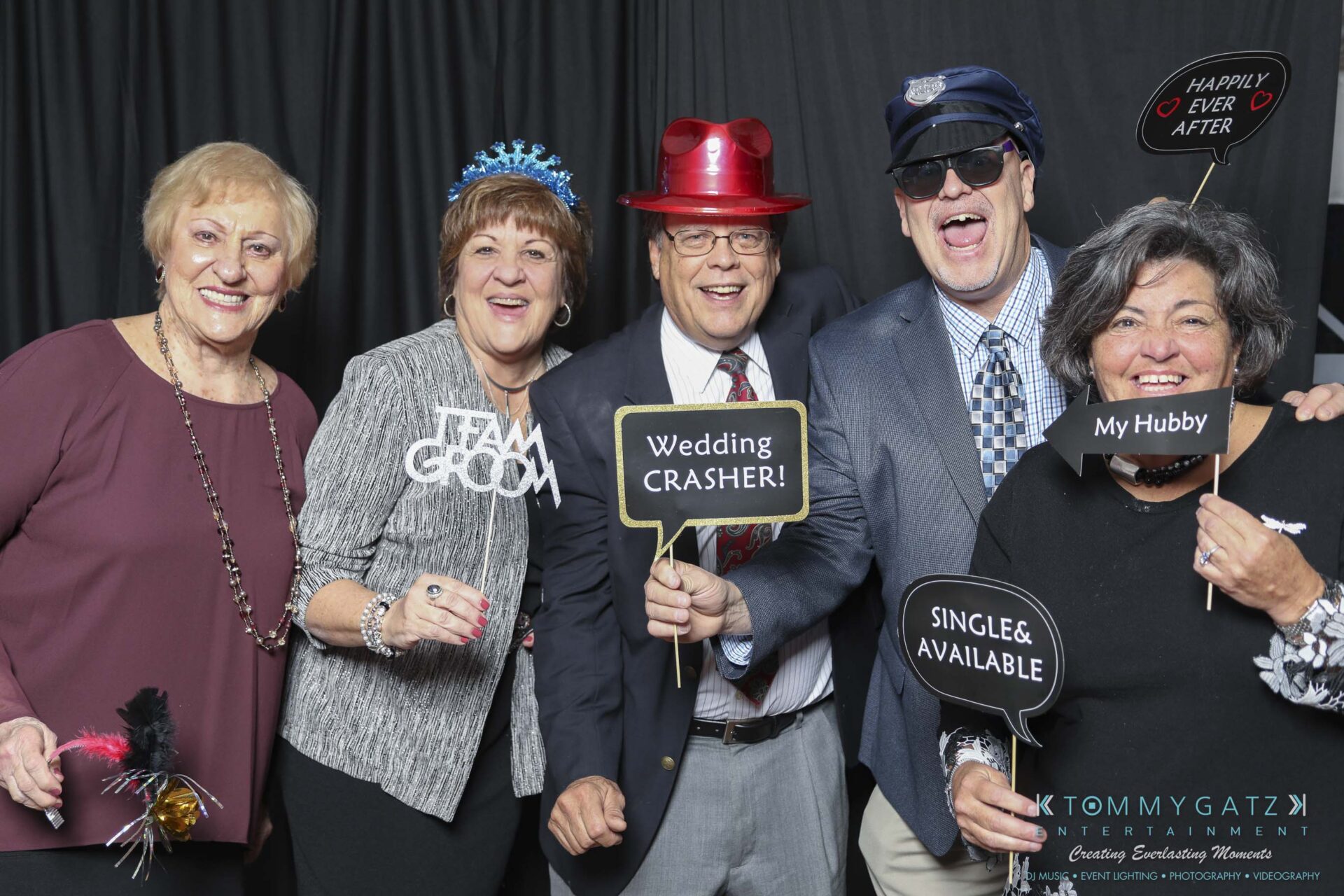 Megan-Matt-102718-Blow-WM-7 - TOMMY GATZ ENTERTAINMENT A group of five people in party attire pose with playful signs and props against a dark backdrop.