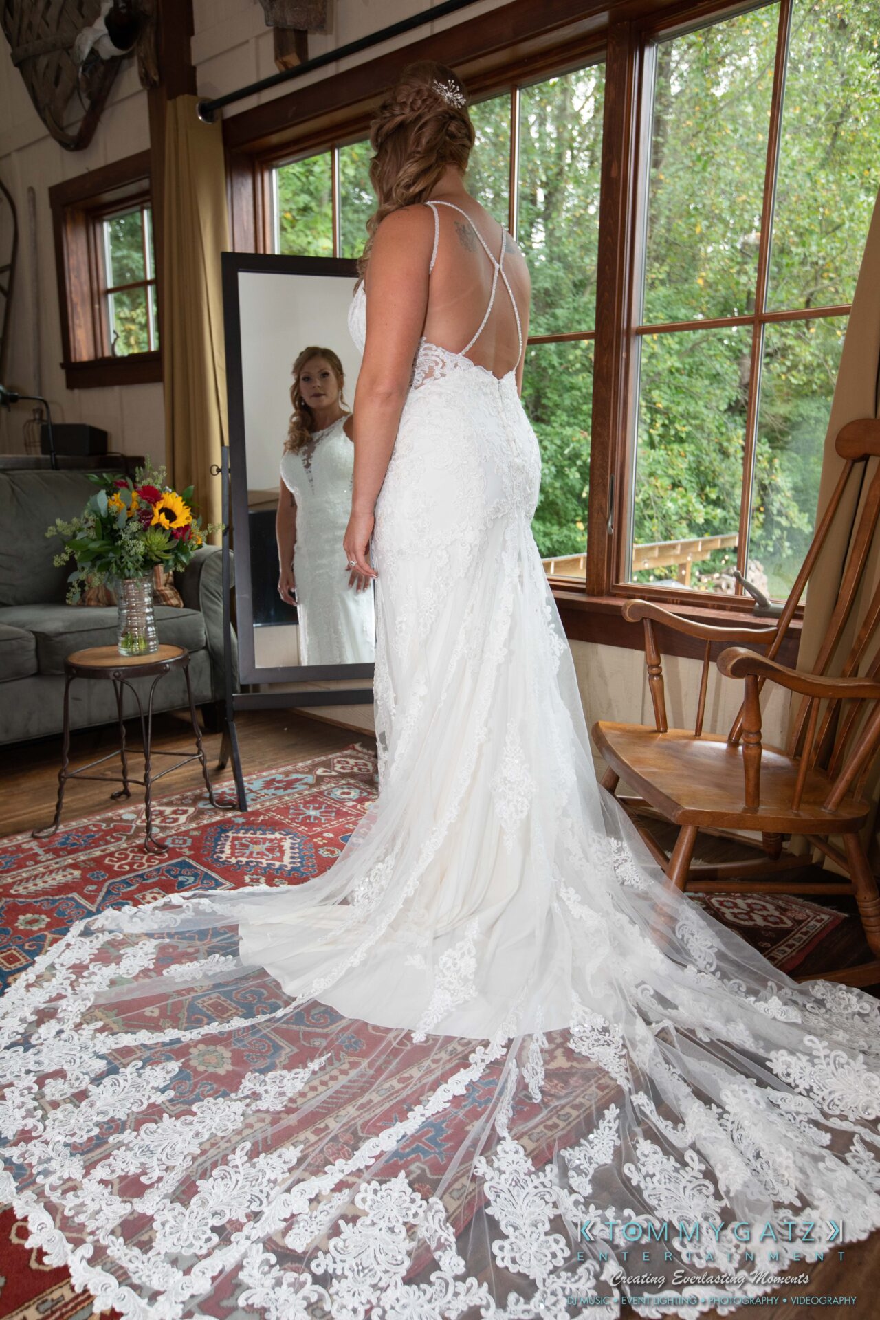 091419-Proctor-Wedding-FINALS-PreCeremony-Low-Res-WM-66 - TOMMY GATZ ENTERTAINMENT A bride in a white lace gown with a long train stands in front of a mirror.