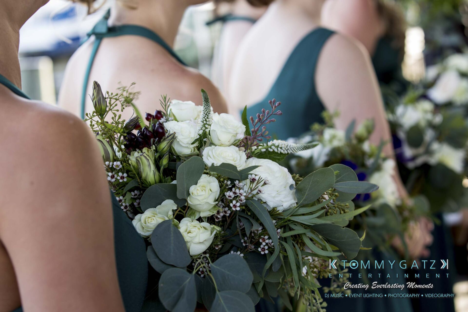 Amanda-Tyler-102117-CEREMONY-Low-Res-WM-25 - TOMMY GATZ ENTERTAINMENT Bridesmaids in green dresses holding bouquets of white and green flowers, standing in a row.