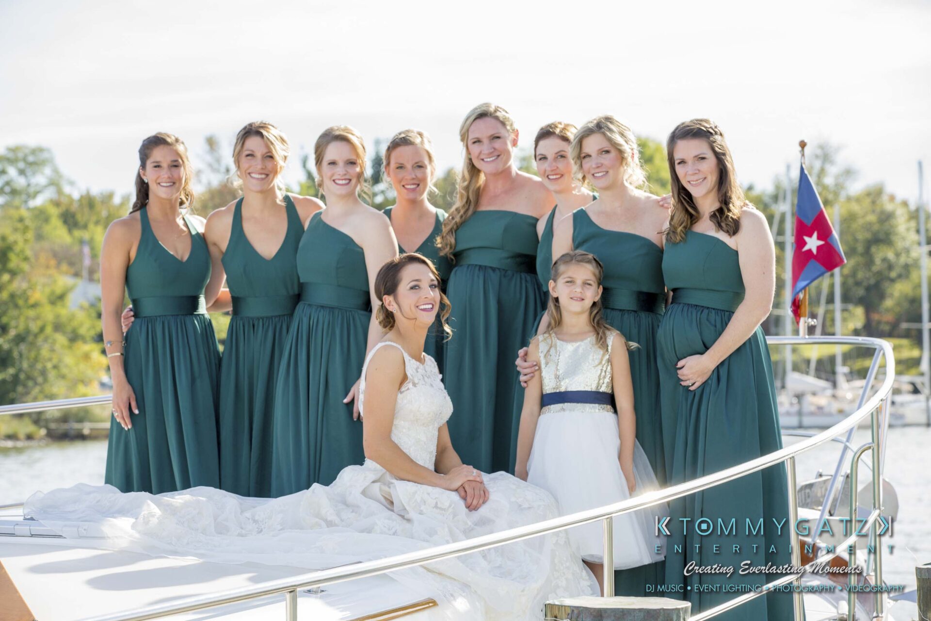 Amanda-Tyler-102117-PREP-Low-Res-WM-103 - TOMMY GATZ ENTERTAINMENT A bride sits on a boat with nine bridesmaids in green dresses standing around her, next to a small girl in a white dress.