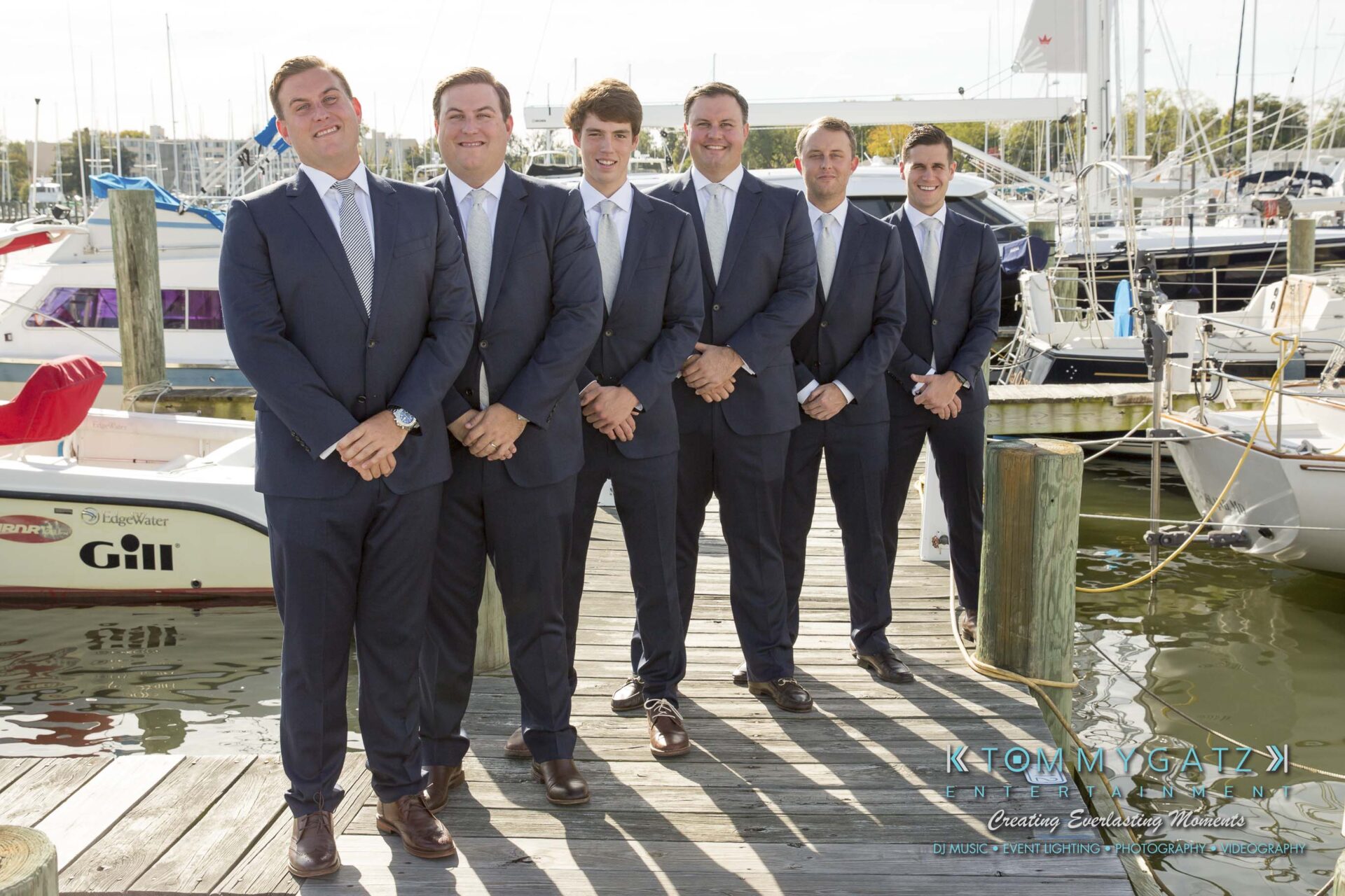 Amanda-Tyler-102117-PREP-Low-Res-WM-106 - TOMMY GATZ ENTERTAINMENT Six men in suits stand on a dock in front of moored boats, smiling at the camera.