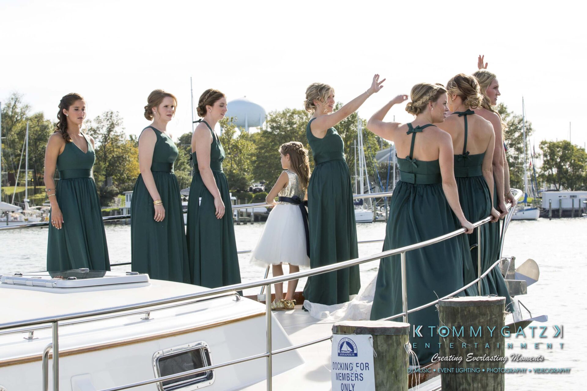 Amanda-Tyler-102117-PREP-Low-Res-WM-119 - TOMMY GATZ ENTERTAINMENT A group of women and a girl in green dresses stand on a boat near a marina. Some women are gesturing while others look around.