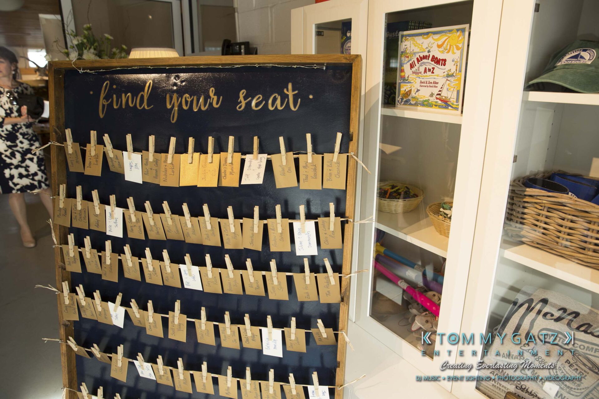 Amanda-Tyler-102117-PREP-Low-Res-WM-188 - TOMMY GATZ ENTERTAINMENT A seating chart display with cards clipped to strings. A cabinet with various items is in the background.
