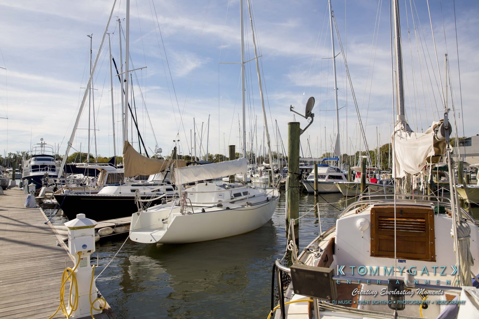 Amanda-Tyler-102117-PREP-Low-Res-WM-20 - TOMMY GATZ ENTERTAINMENT A marina with several sailboats and yachts docked along a wooden pier on a sunny day.