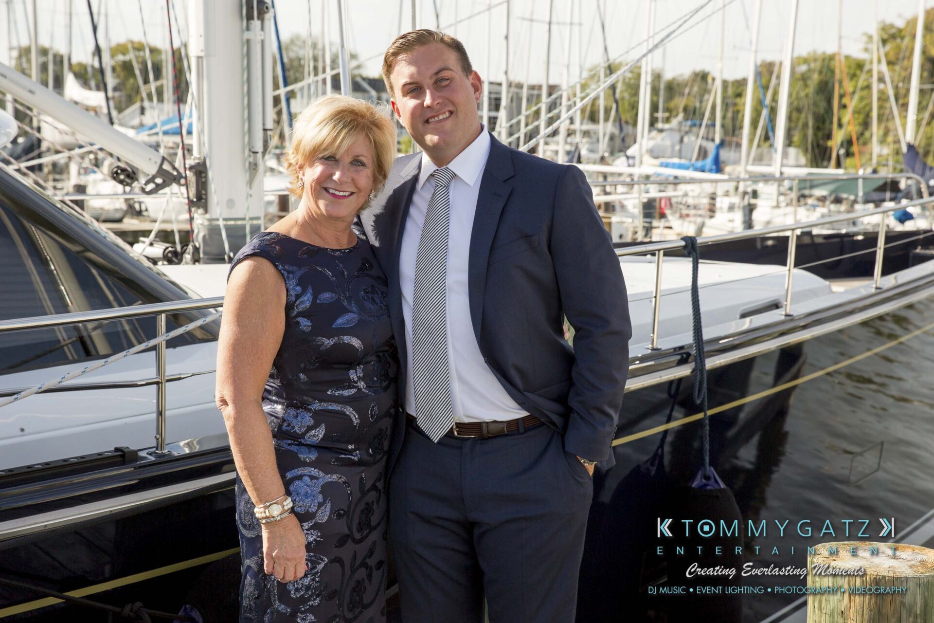 Amanda-Tyler-102117-PREP-Low-Res-WM-93 - TOMMY GATZ ENTERTAINMENT A man and a woman pose in formal attire in front of a docked yacht, smiling at the camera.
