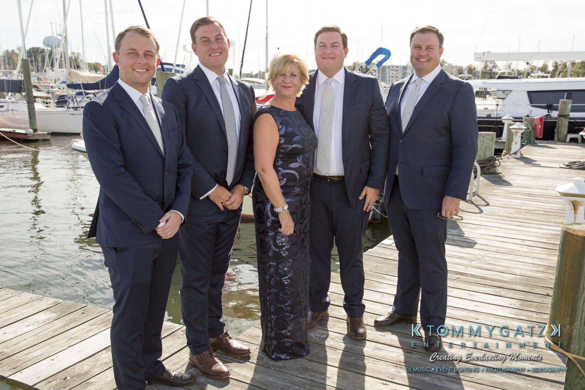 Amanda-Tyler-102117-PREP-Low-Res-WM-99 - TOMMY GATZ ENTERTAINMENT Five people in formal attire stand on a dock with boats in the background.