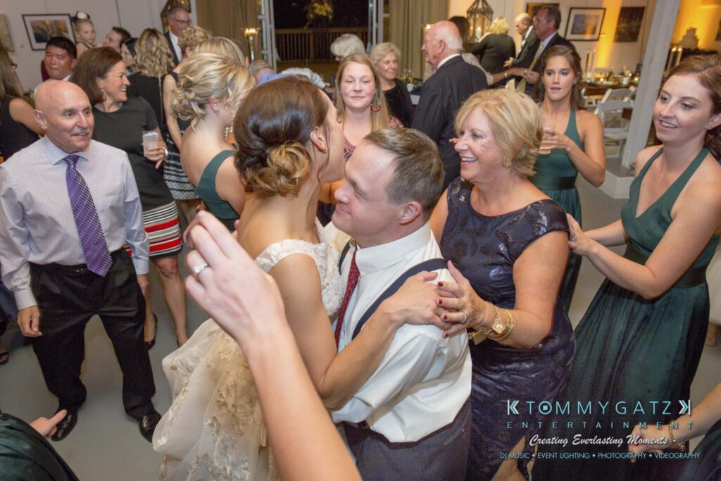 Amanda-Tyler-102117-RECEPTION-Low-Res-WM-107 - TOMMY GATZ ENTERTAINMENT A joyful wedding celebration with guests dancing and mingling in a bright room.