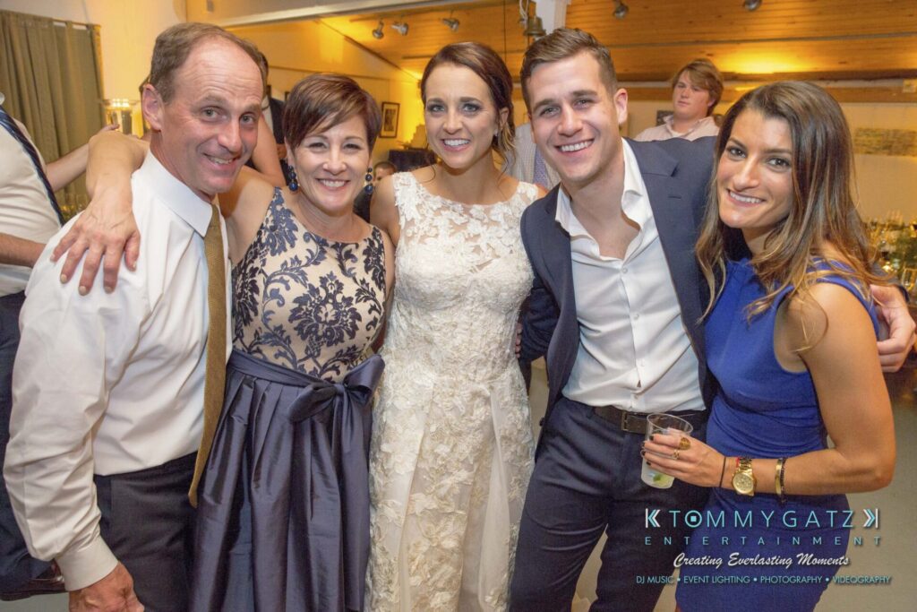Five people dressed in formal attire smiling and posing together at a social event.