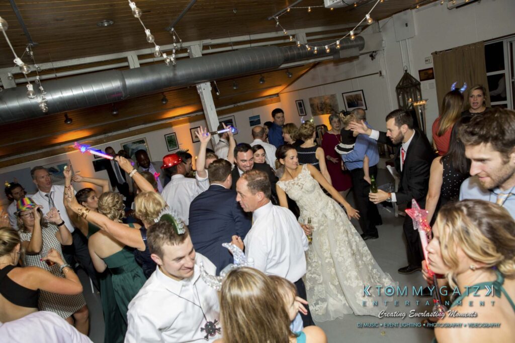 A group of people dancing and socializing at an indoor wedding reception.