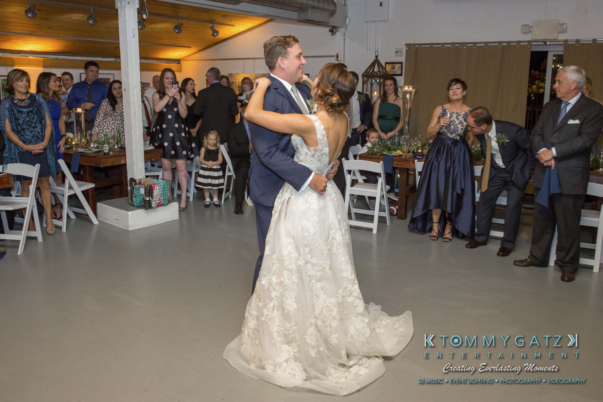 Amanda-Tyler-102117-RECEPTION-Low-Res-WM-44 - TOMMY GATZ ENTERTAINMENT A couple shares a first dance at a wedding reception, surrounded by guests seated and standing.