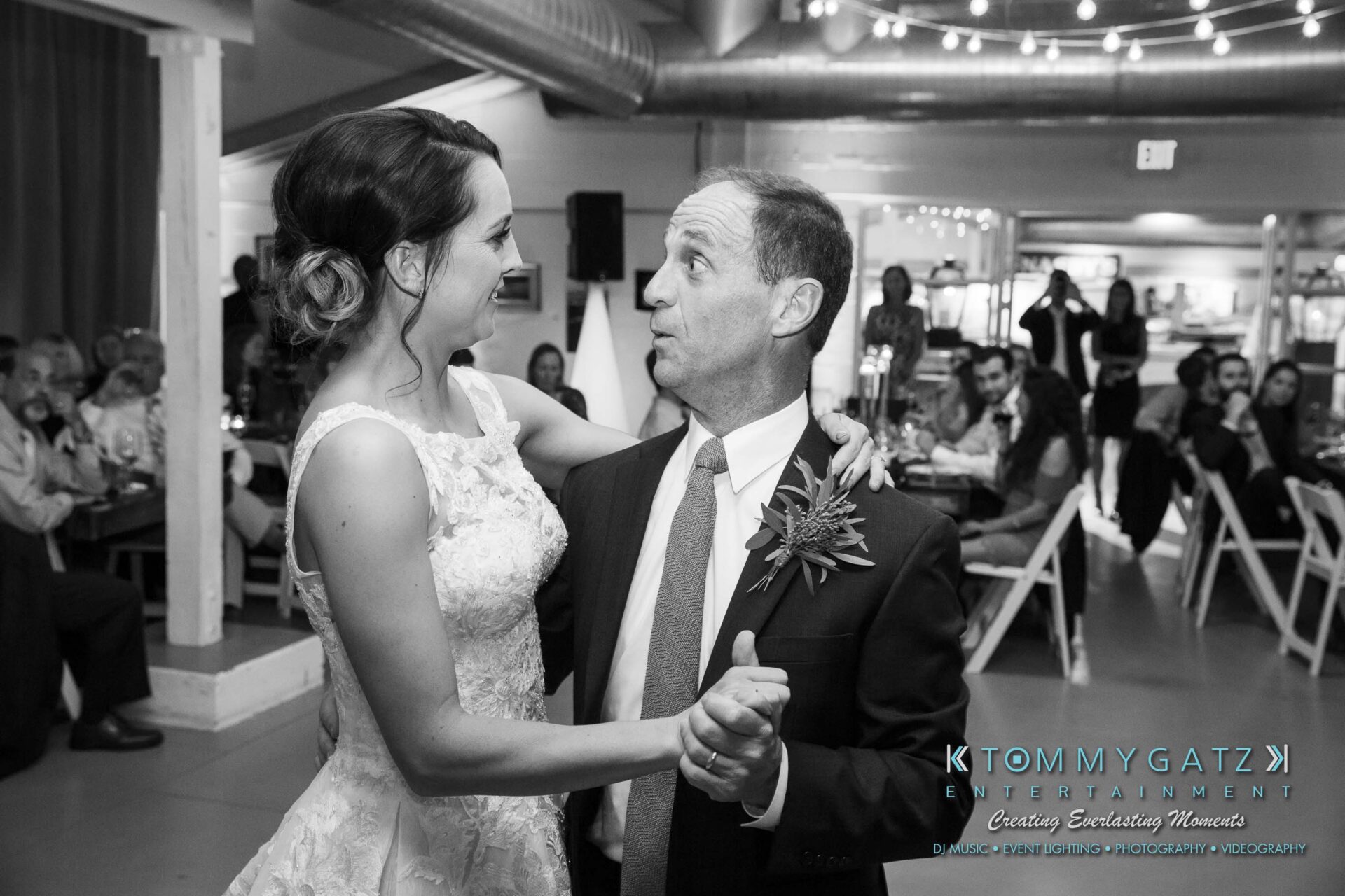 Amanda-Tyler-102117-RECEPTION-Low-Res-WM-69 - TOMMY GATZ ENTERTAINMENT A bride and an older man dance together at a wedding reception, surrounded by seated guests in a decorated venue.