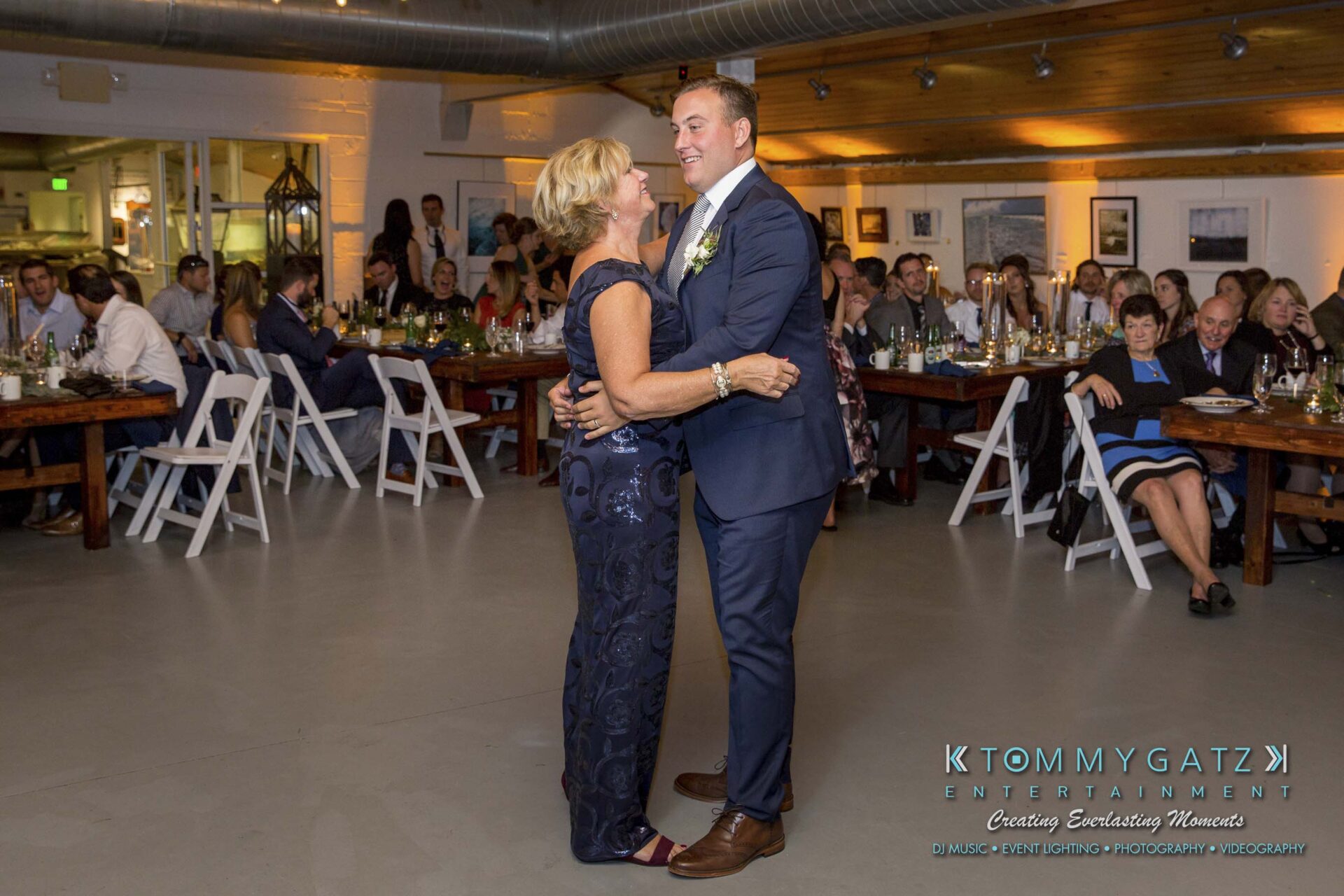 Amanda-Tyler-102117-RECEPTION-Low-Res-WM-75 - TOMMY GATZ ENTERTAINMENT A man and a woman dance together in a formal setting with seated guests watching.