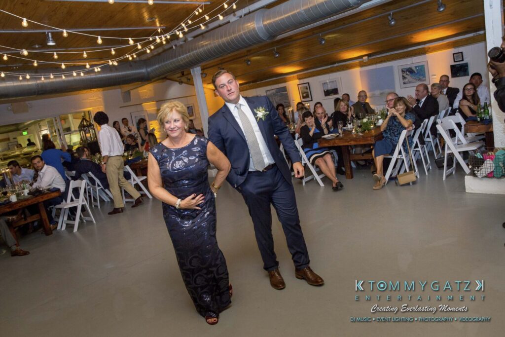 Amanda-Tyler-102117-RECEPTION-Low-Res-WM-83 - TOMMY GATZ ENTERTAINMENT A man and woman walk together at an indoor event with seated guests in the background.