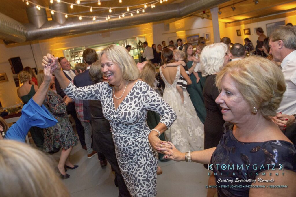 People dancing and smiling at a festive indoor event with string lights overhead.