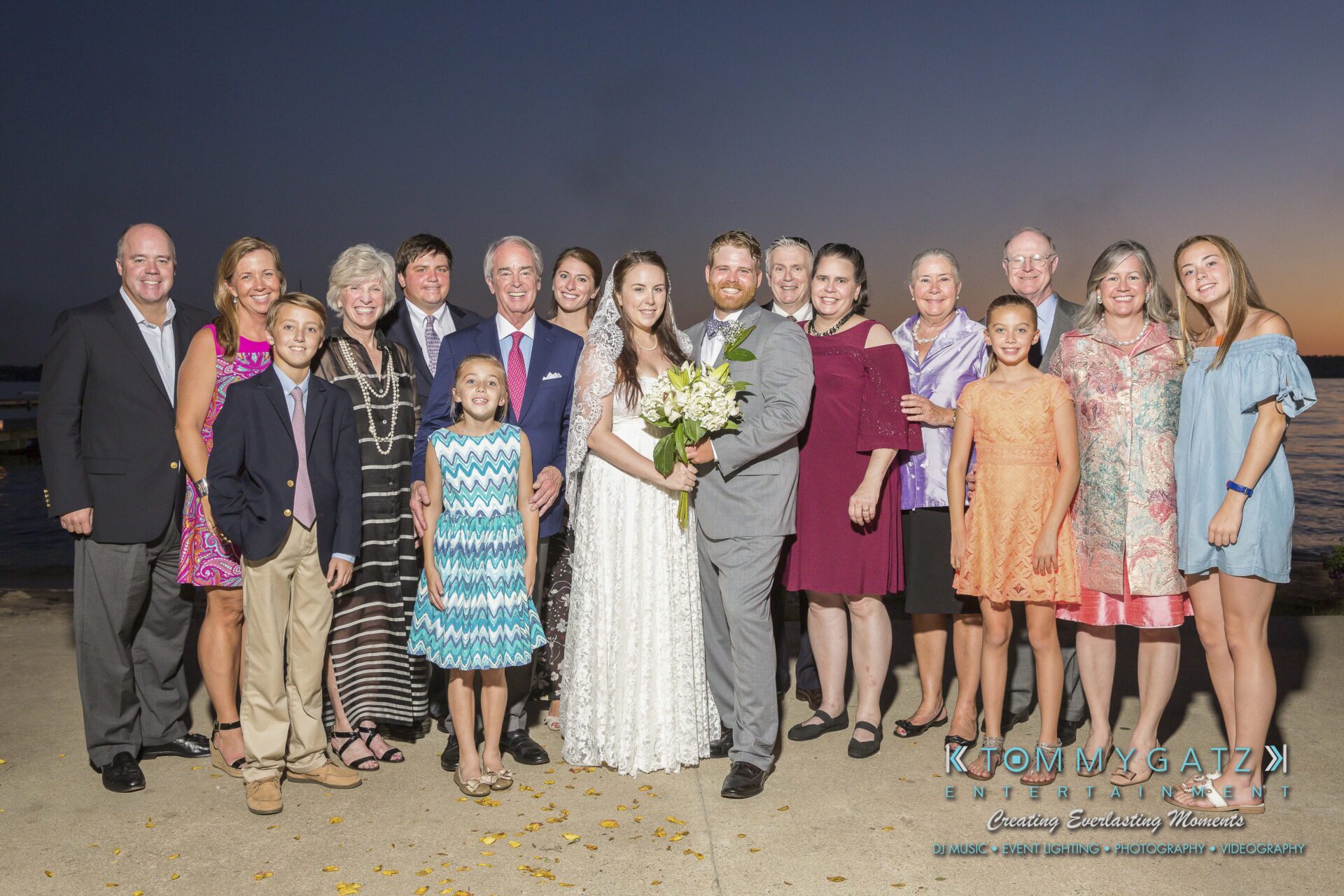 Ann-Marie-Alex-92317-FORMALS-Low-Res-WM-100 - TOMMY GATZ ENTERTAINMENT A group of people posing outdoors at sunset, with a couple in wedding attire in the center.
