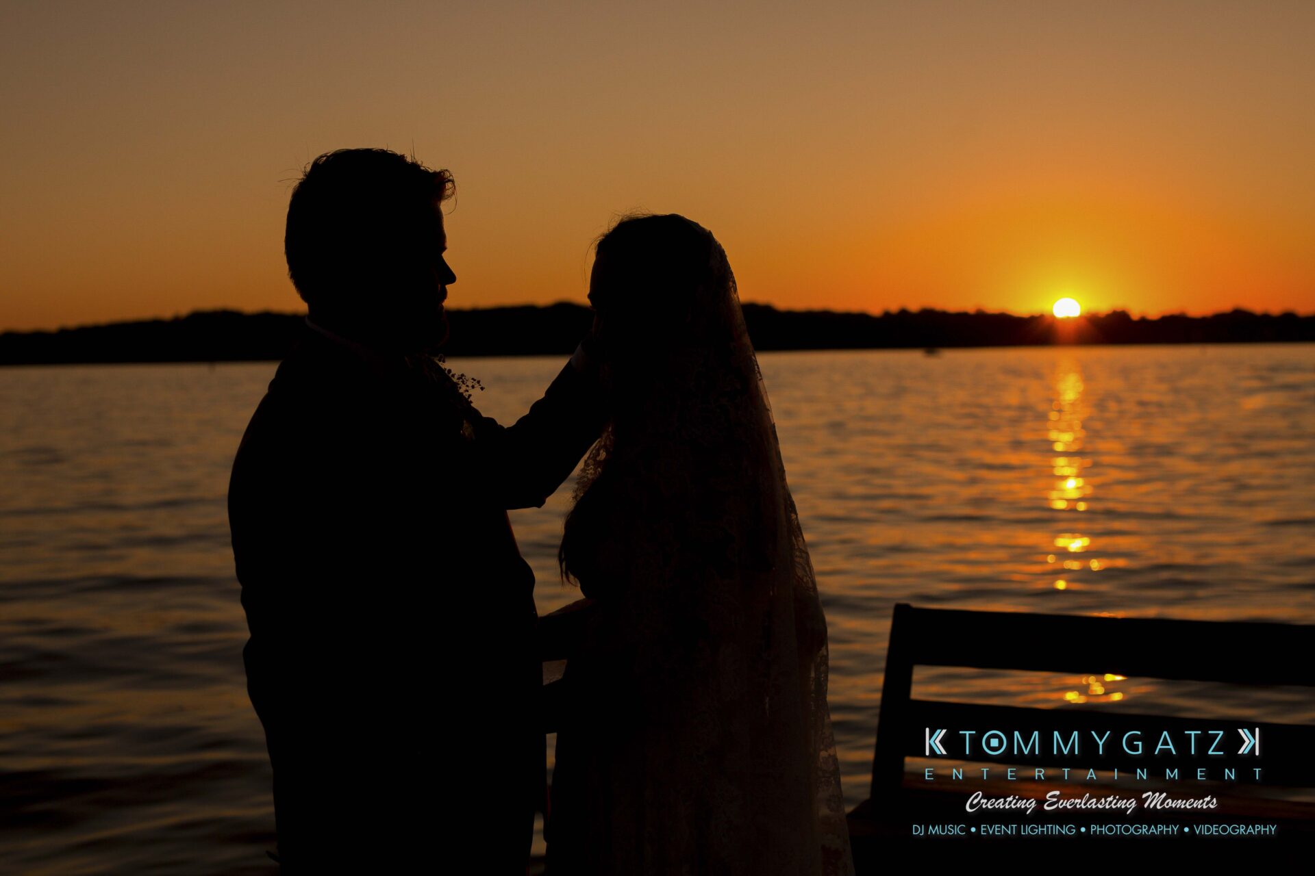Ann-Marie-Alex-92317-FORMALS-Low-Res-WM-70 - TOMMY GATZ ENTERTAINMENT Silhouetted couple standing by a lake at sunset, with the sun setting on the horizon.