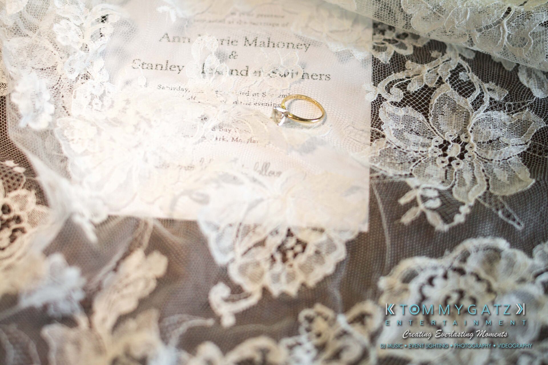 Ann-Marie-Alex-92317-PREP-Low-Res-WM-1 - TOMMY GATZ ENTERTAINMENT A lace veil overlay on a wedding invitation with a gold ring placed on top.