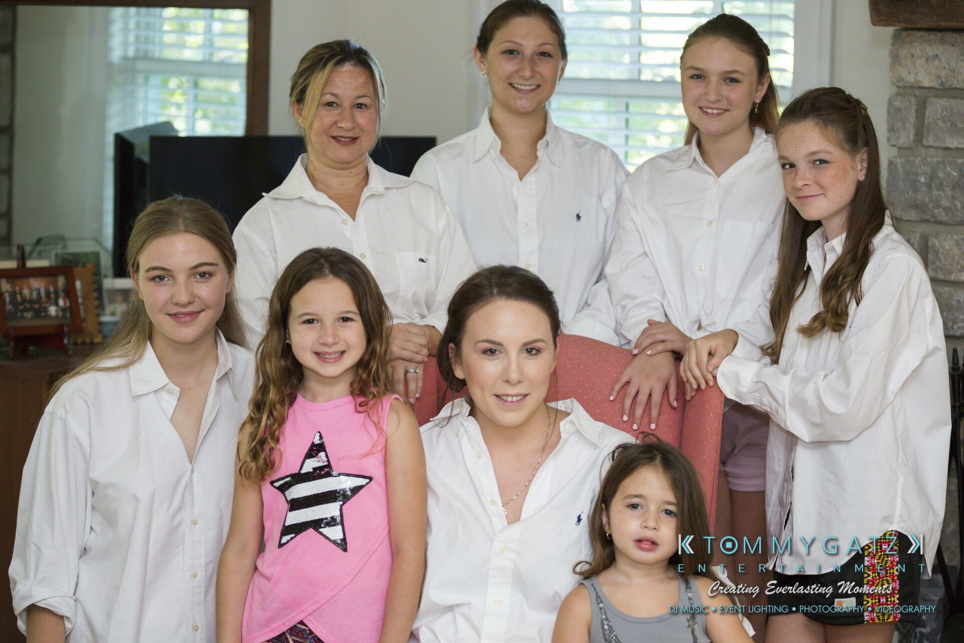 Ann-Marie-Alex-92317-PREP-Low-Res-WM-112 - TOMMY GATZ ENTERTAINMENT A group of seven people, consisting of five adults in white shirts and two children, pose indoors in front of a window. One child wears a pink star shirt.