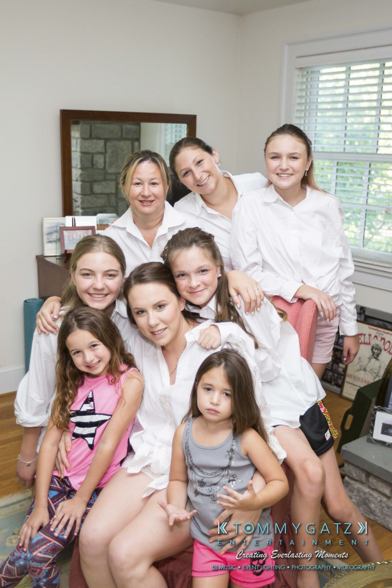 Ann-Marie-Alex-92317-PREP-Low-Res-WM-114 - TOMMY GATZ ENTERTAINMENT A group of seven people, including five adults and two children, pose indoors for a photo. They are smiling and casually dressed, sitting and standing close together.