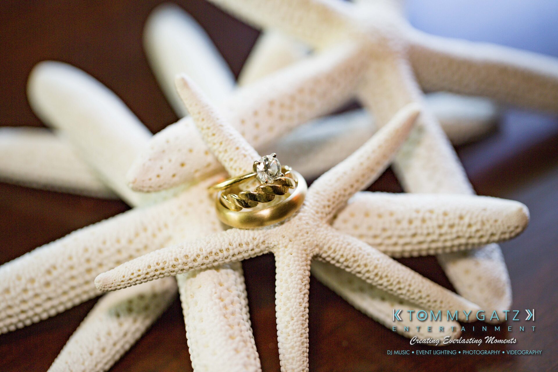Ann-Marie-Alex-92317-PREP-Low-Res-WM-71 - TOMMY GATZ ENTERTAINMENT Gold wedding and engagement rings resting on white starfish.
