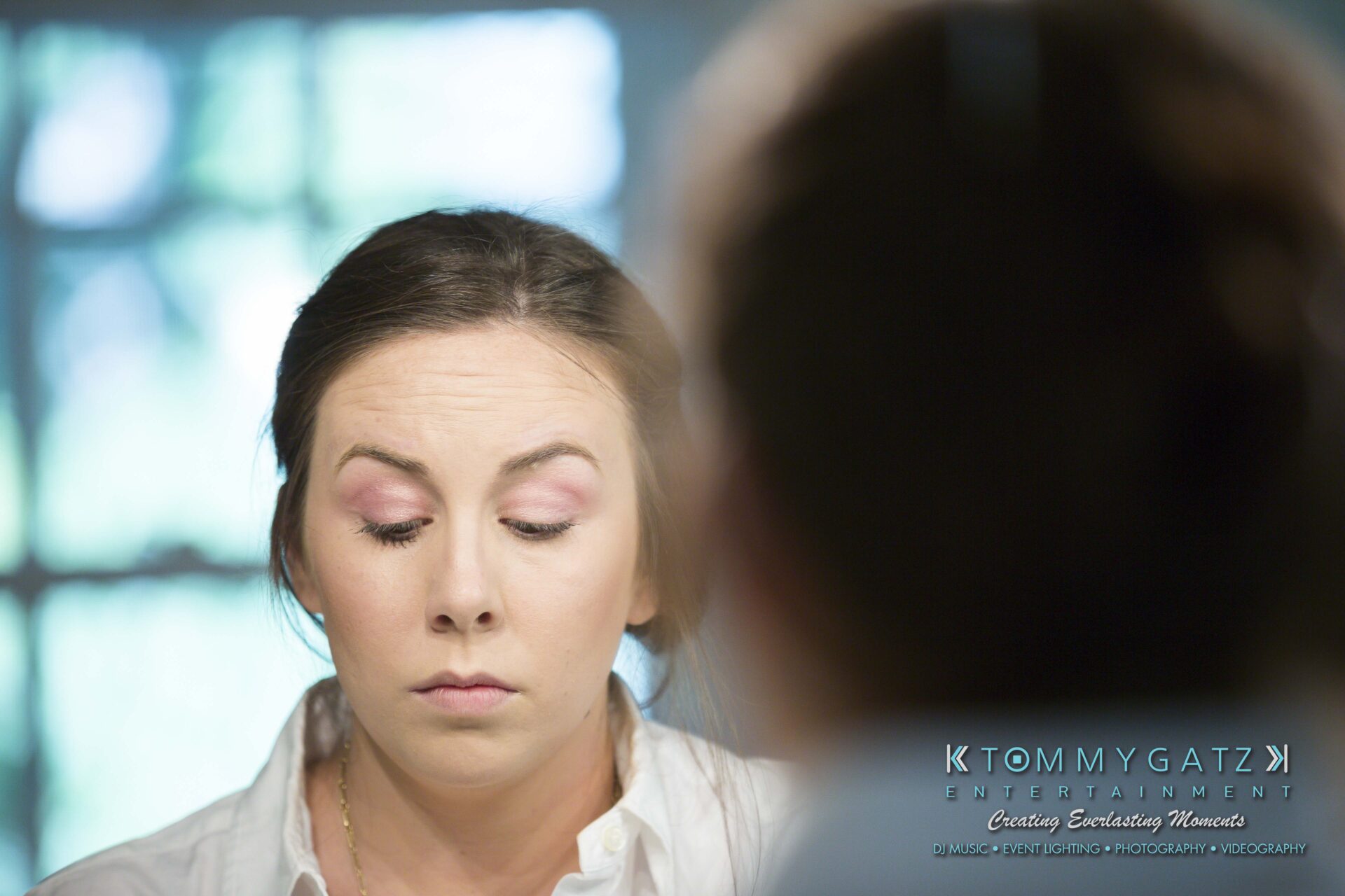 Ann-Marie-Alex-92317-PREP-Low-Res-WM-89 - TOMMY GATZ ENTERTAINMENT A woman with eyes closed, wearing light makeup, is seen through a mirror. A blurred window scene is in the background.