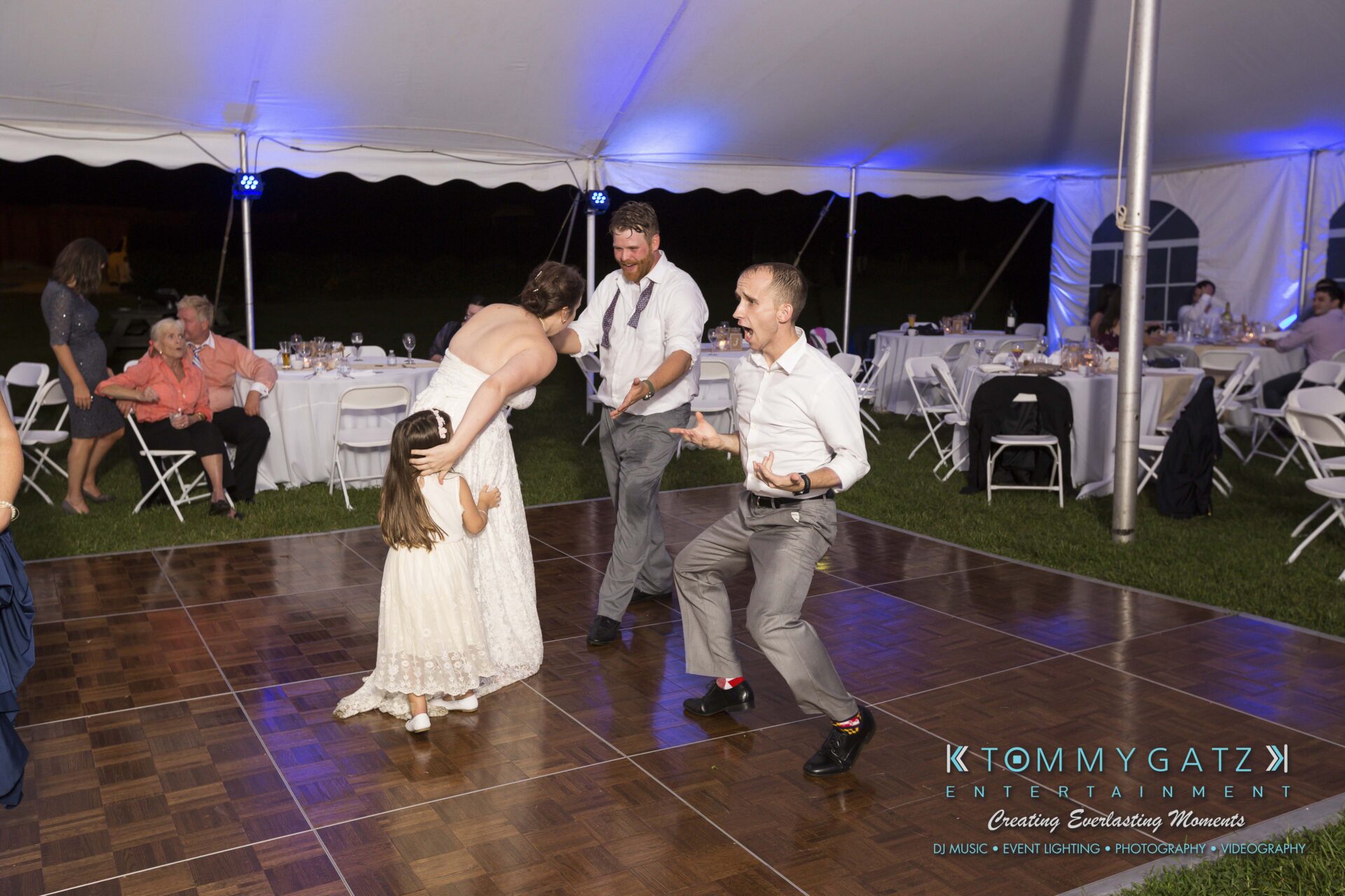 Ann-Marie-Alex-92317-RECEPTION-Low-Res-WM-116 - TOMMY GATZ ENTERTAINMENT People dancing joyfully on a wooden dance floor in an outdoor tented event.