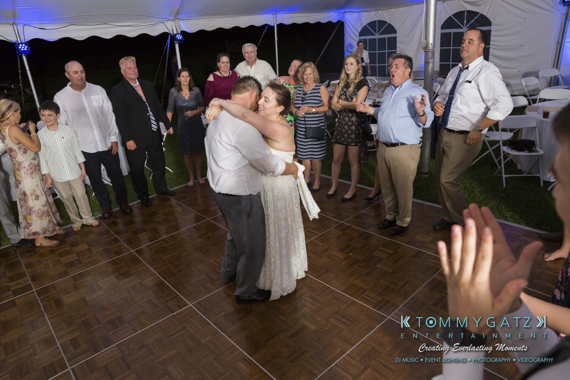 Ann-Marie-Alex-92317-RECEPTION-Low-Res-WM-130 - TOMMY GATZ ENTERTAINMENT A couple dances in the center of a tented reception, surrounded by clapping guests.