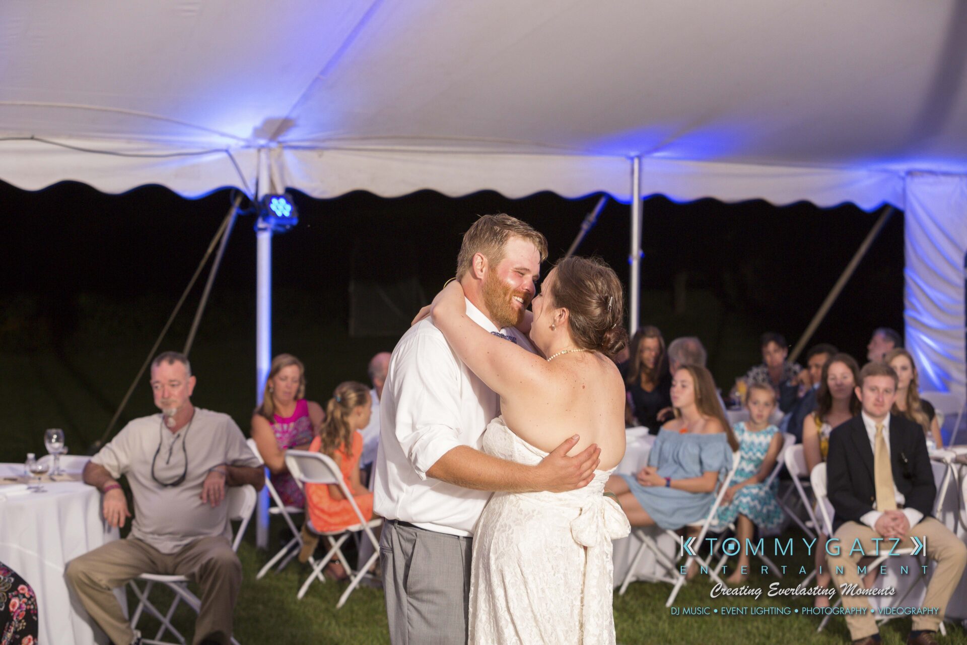 Ann-Marie-Alex-92317-RECEPTION-Low-Res-WM-56 - TOMMY GATZ ENTERTAINMENT A couple shares a dance under a tent at a wedding reception, surrounded by seated guests.