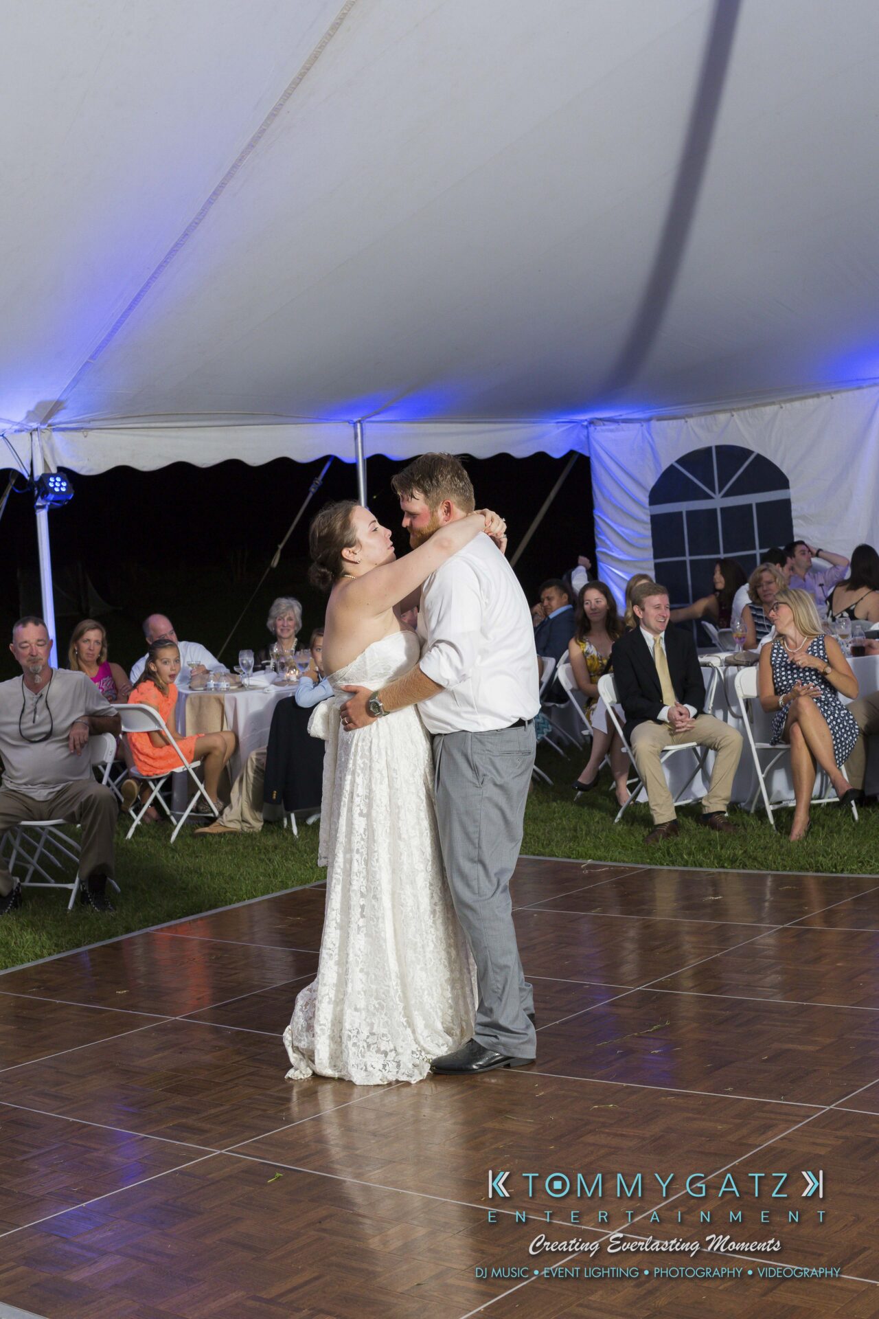 Ann-Marie-Alex-92317-RECEPTION-Low-Res-WM-61 - TOMMY GATZ ENTERTAINMENT A couple dances under a white tent at a wedding reception, surrounded by seated guests.