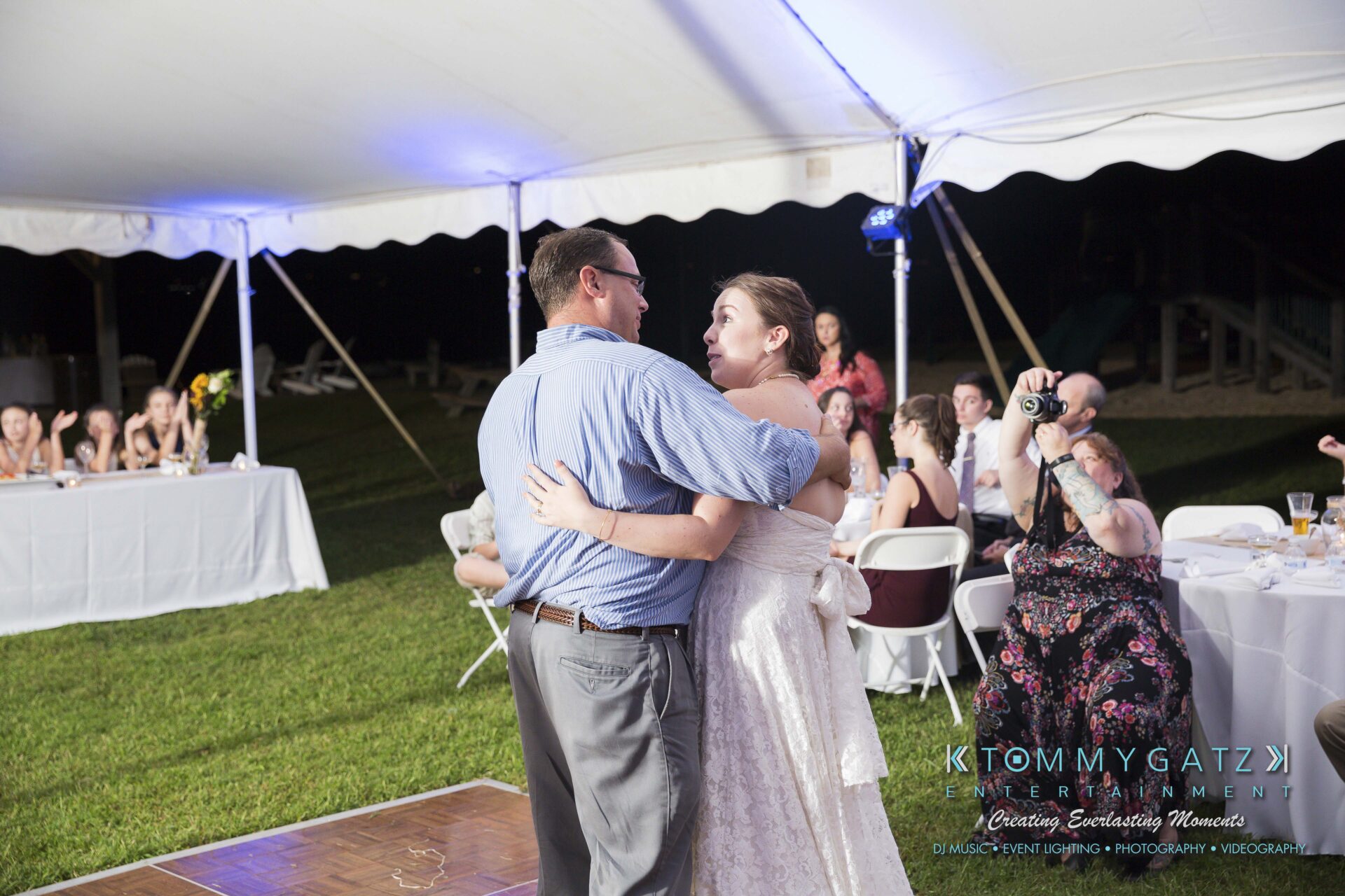 Ann-Marie-Alex-92317-RECEPTION-Low-Res-WM-65 - TOMMY GATZ ENTERTAINMENT Couple dancing under a tent at an outdoor event, surrounded by seated guests.
