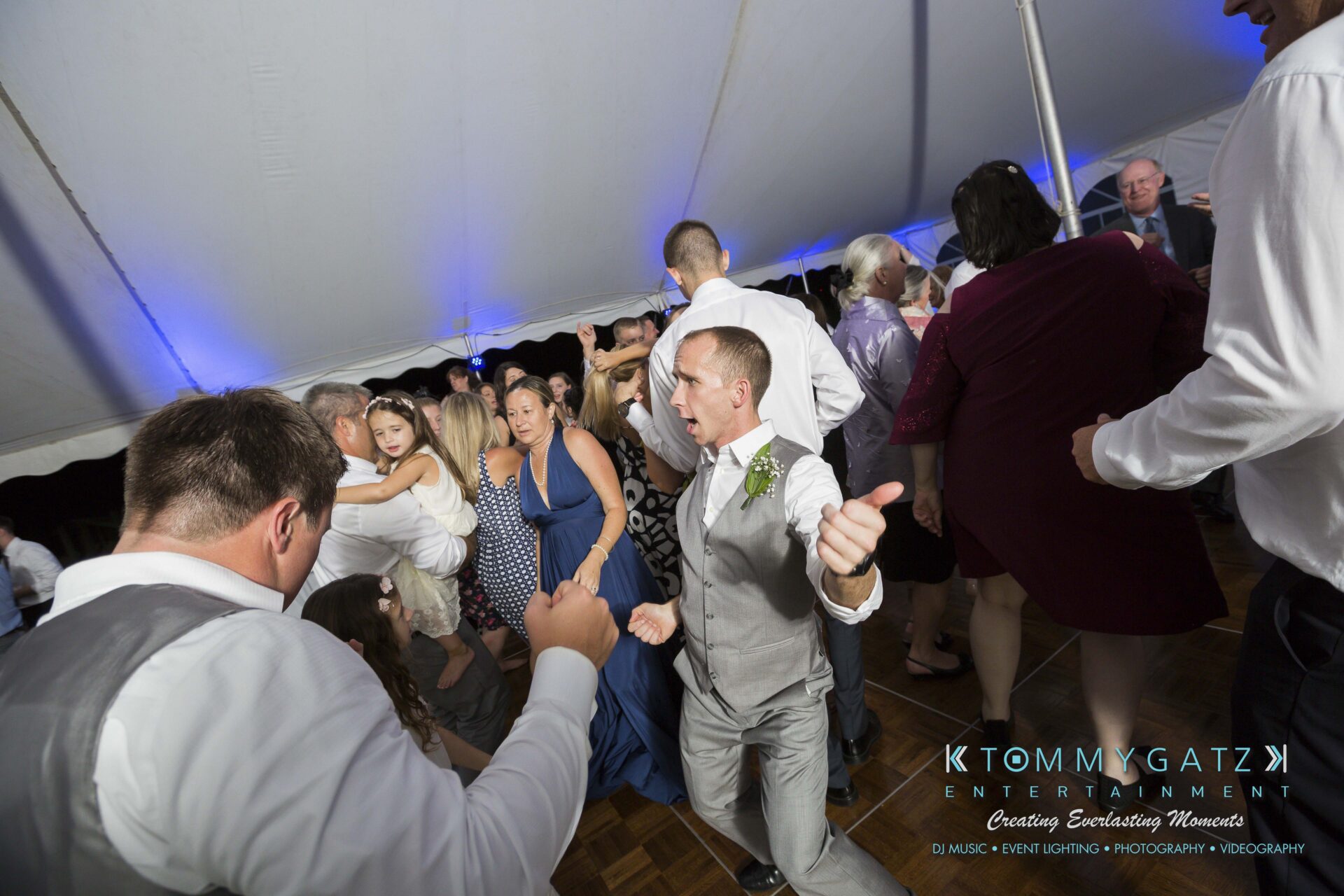 Ann-Marie-Alex-92317-RECEPTION-Low-Res-WM-94 - TOMMY GATZ ENTERTAINMENT People dancing energetically at a wedding reception under a tent, with a DJ booth visible in the background.