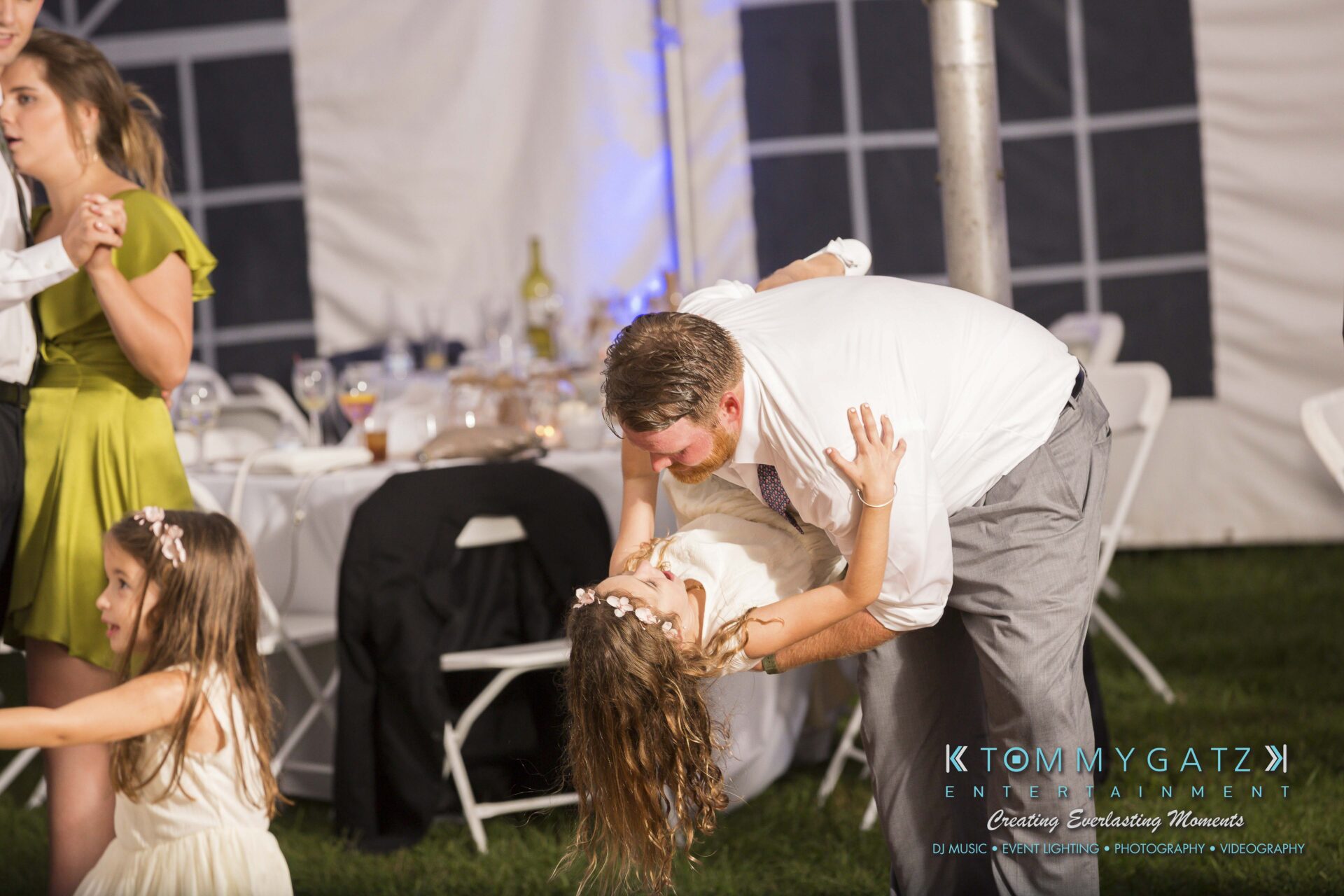 Ann-Marie-Alex-92317-RECEPTION-Low-Res-WM-95 - TOMMY GATZ ENTERTAINMENT A man dances with a young girl at an outdoor event, surrounded by people, tables, and chairs.