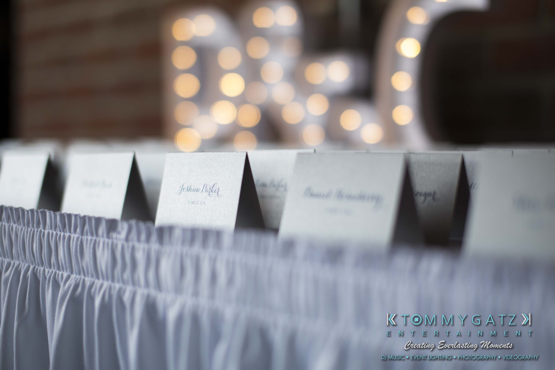 Carly-Patrick-FINAL-Blog-Watermark-2 - TOMMY GATZ ENTERTAINMENT Place cards arranged in a row on a table covered with a white cloth.