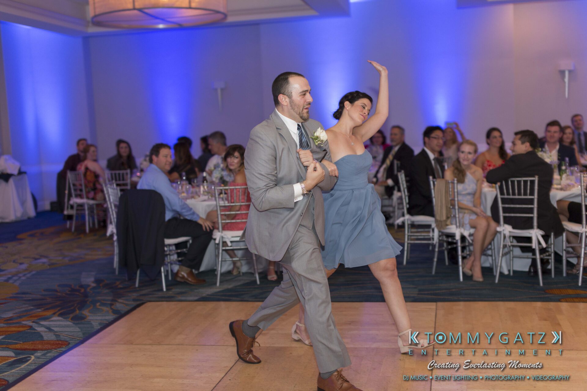 Carly-Patrick-FINAL-Blog-Watermark-32 - TOMMY GATZ ENTERTAINMENT A couple in formal attire dances energetically at a wedding reception, with seated guests watching in the background.