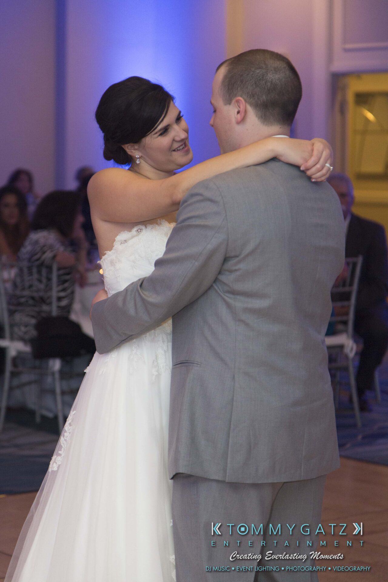 Carly-Patrick-FINAL-Blog-Watermark-35 - TOMMY GATZ ENTERTAINMENT A bride and groom share a dance at their wedding reception, surrounded by guests.